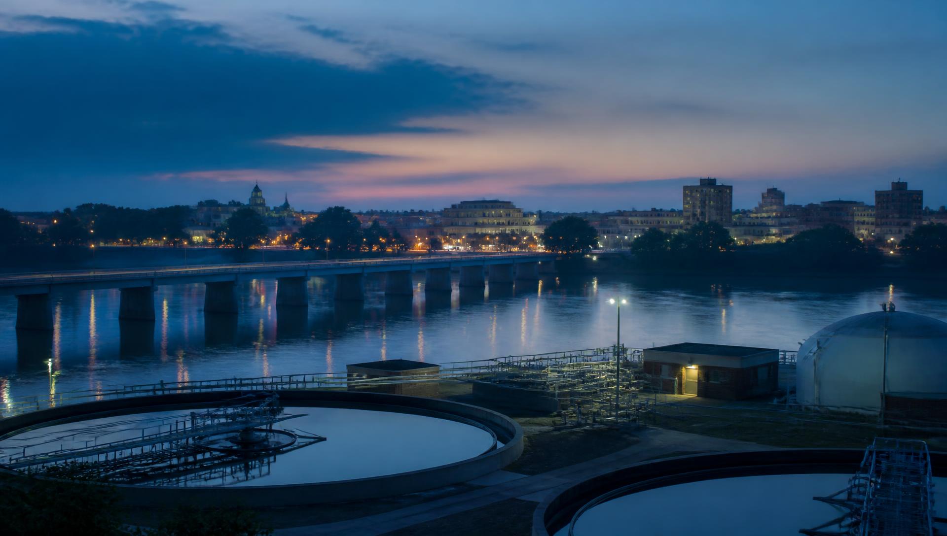 Riverfront cityscape with a municipal water treatment facility at dusk
